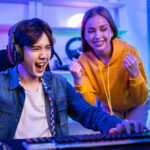 Caucasian Esport couple gamer playing online video game on computer. Handsome man gaming player feel happy and excited, enjoy technology broadcast live streaming while plays cyber tournament at home