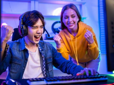 Caucasian Esport couple gamer playing online video game on computer. Handsome man gaming player feel happy and excited, enjoy technology broadcast live streaming while plays cyber tournament at home